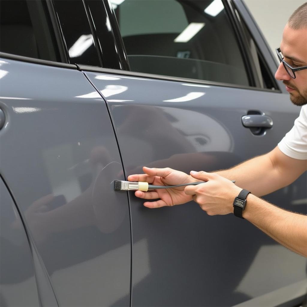 Close-up of a technician performing auto paint touch up on a car scratch