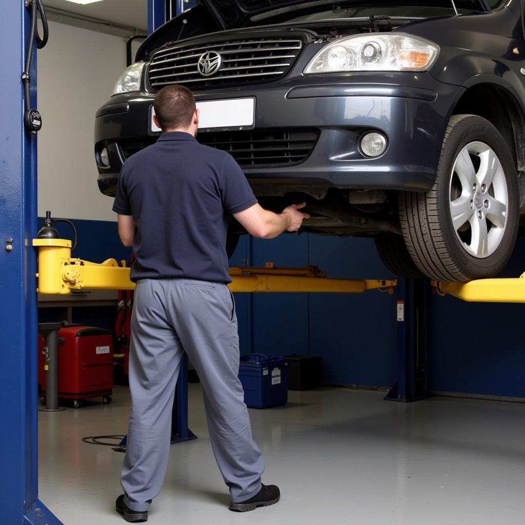 Mechanic performing repairs on a car lifted on a hydraulic lift